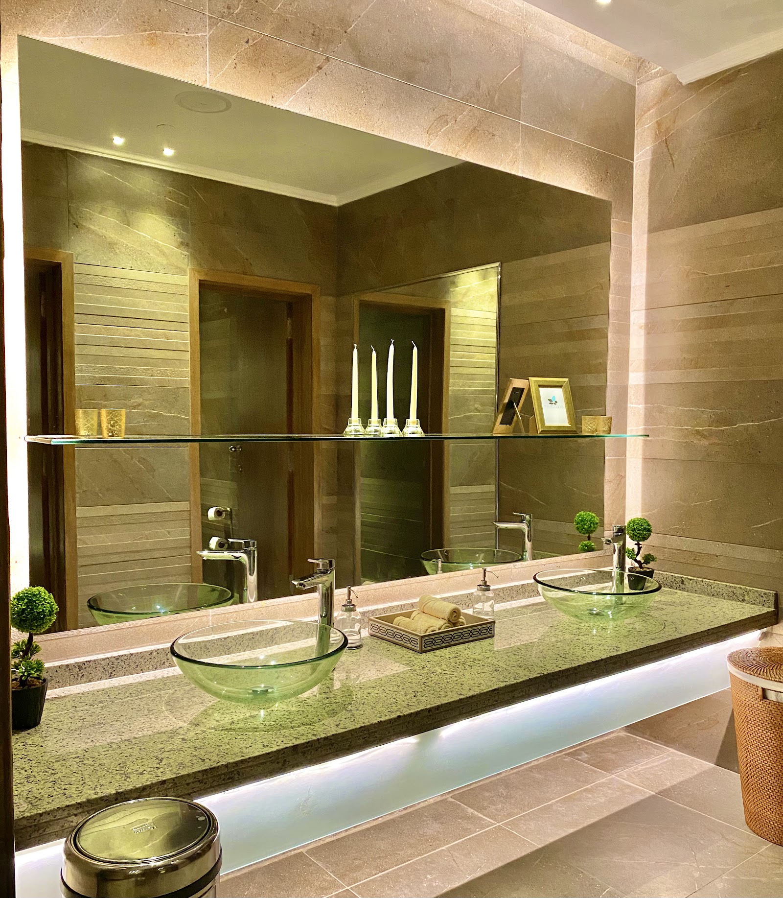 Spa bathroom with dual green glass sinks, illuminated mirror, stone walls, and decorative candles at Steigenberger Resort Alaya Marsa Alam.