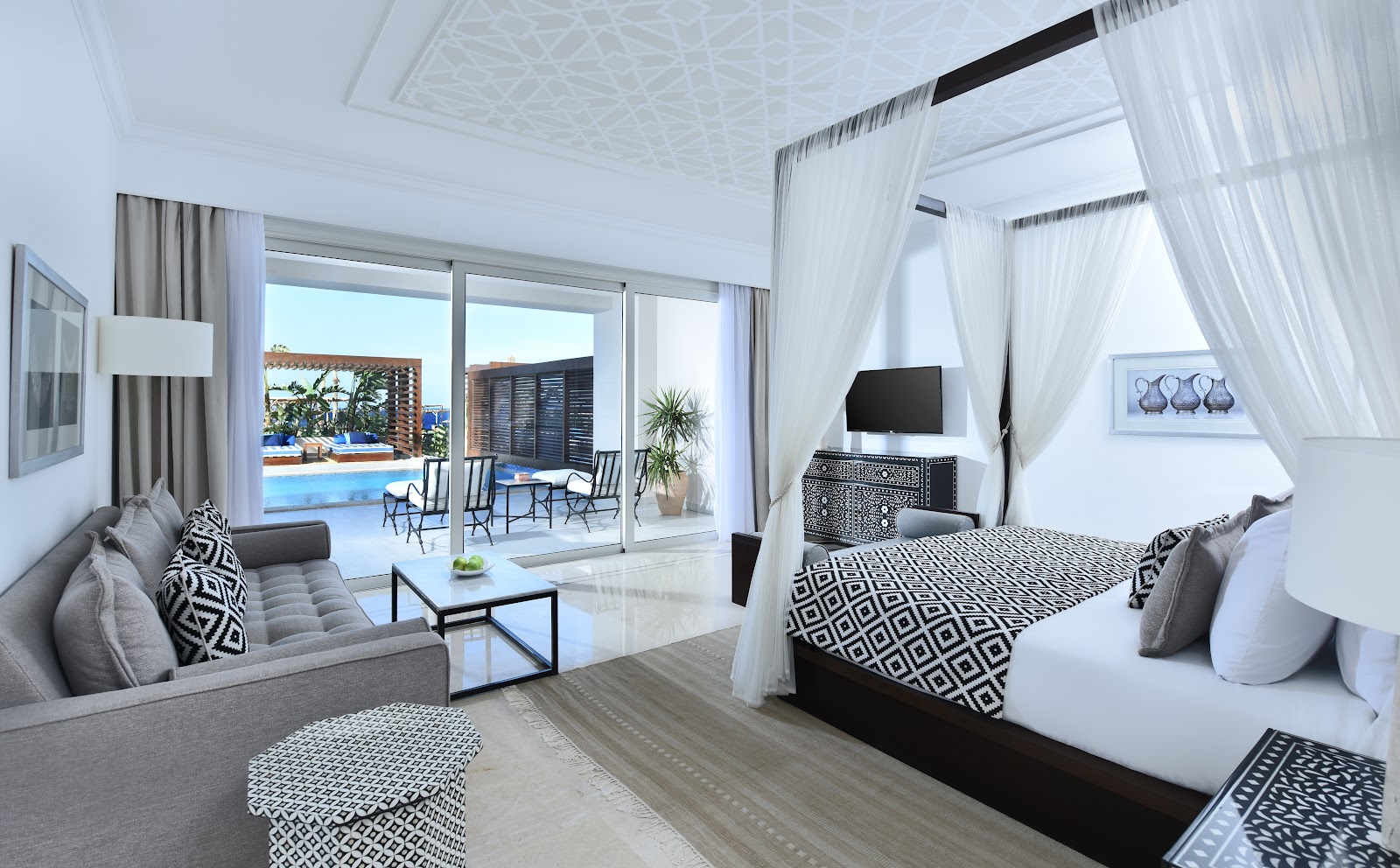 Modern resort room with arched ceiling, bed with patterned runner, desk, and balcony overlooking pool and sea at Steigenberger Resort Alaya Marsa Alam.
