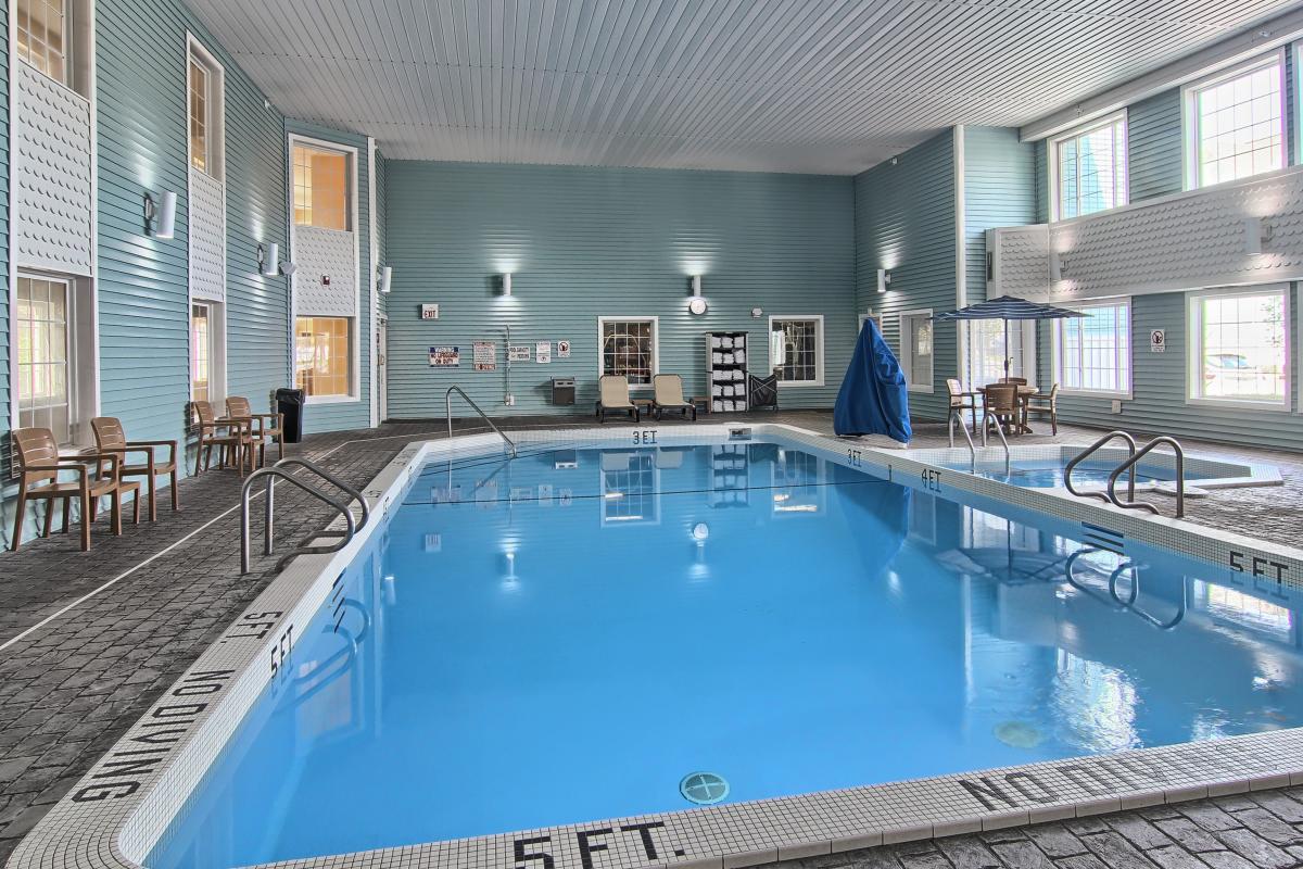 Indoor pool with blue water and metal railings, surrounded by turquoise walls, lounge chairs, and seating areas at Sugar Beach resort.