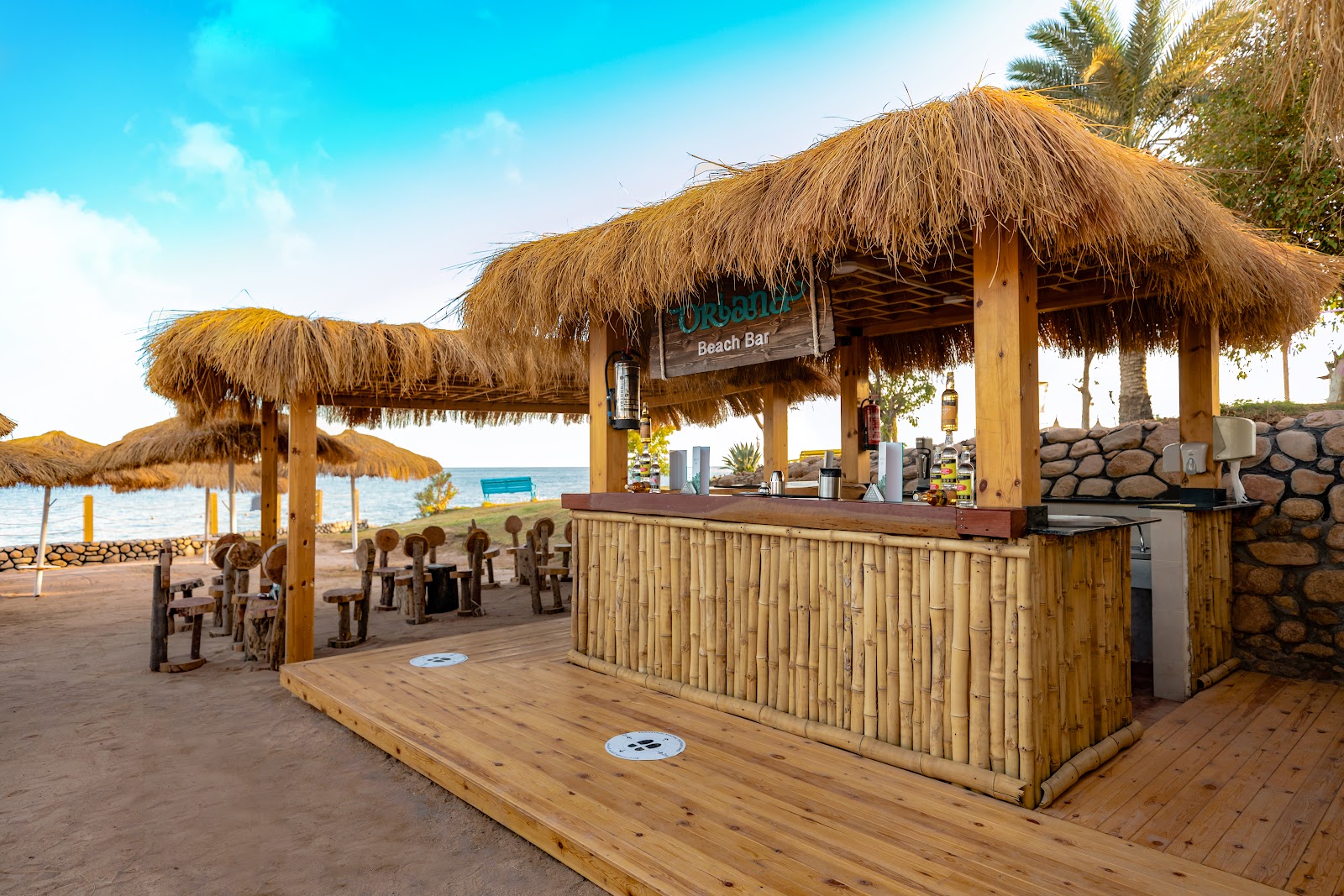 Beach bar with thatched roof and wooden counter at Sunrise Select Diamond Beach Resort, palm trees and ocean visible beyond.