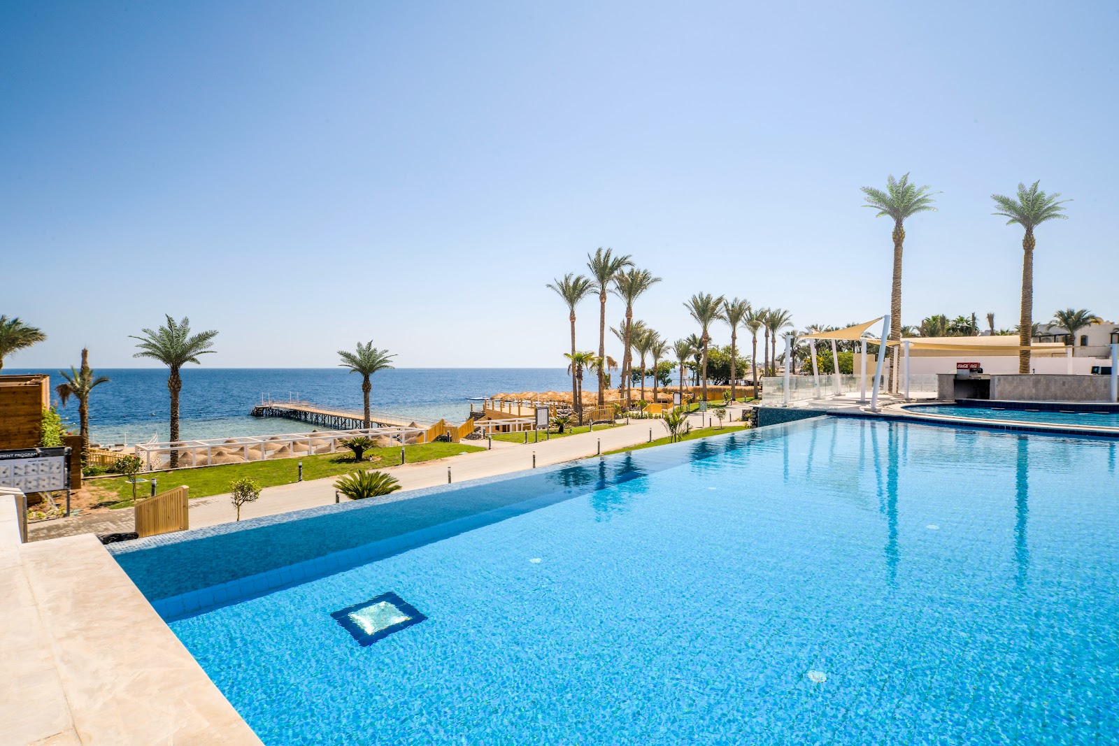 Large turquoise pool overlooks a palm-lined beach and the Mediterranean Sea at Sunrise Select Diamond Beach Resort.