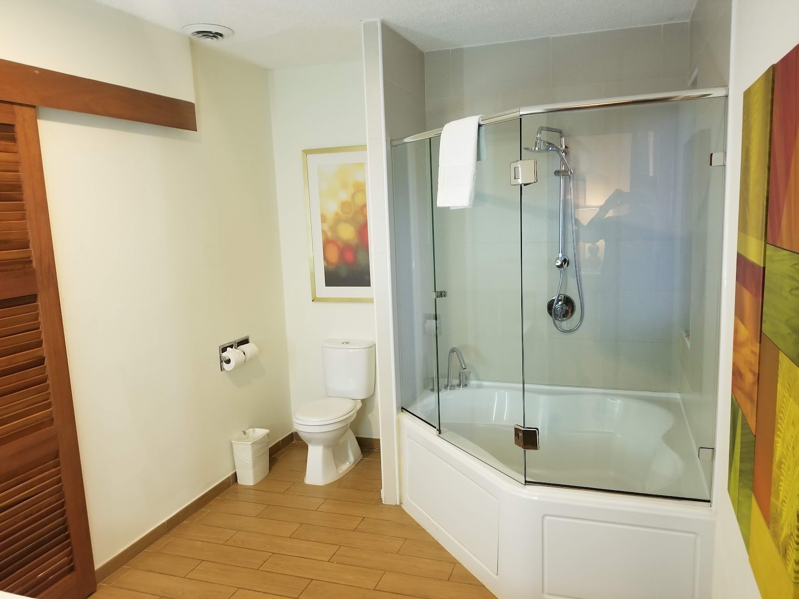Resort bathroom with glass-enclosed shower, white toilet, cream walls, and tile flooring.
