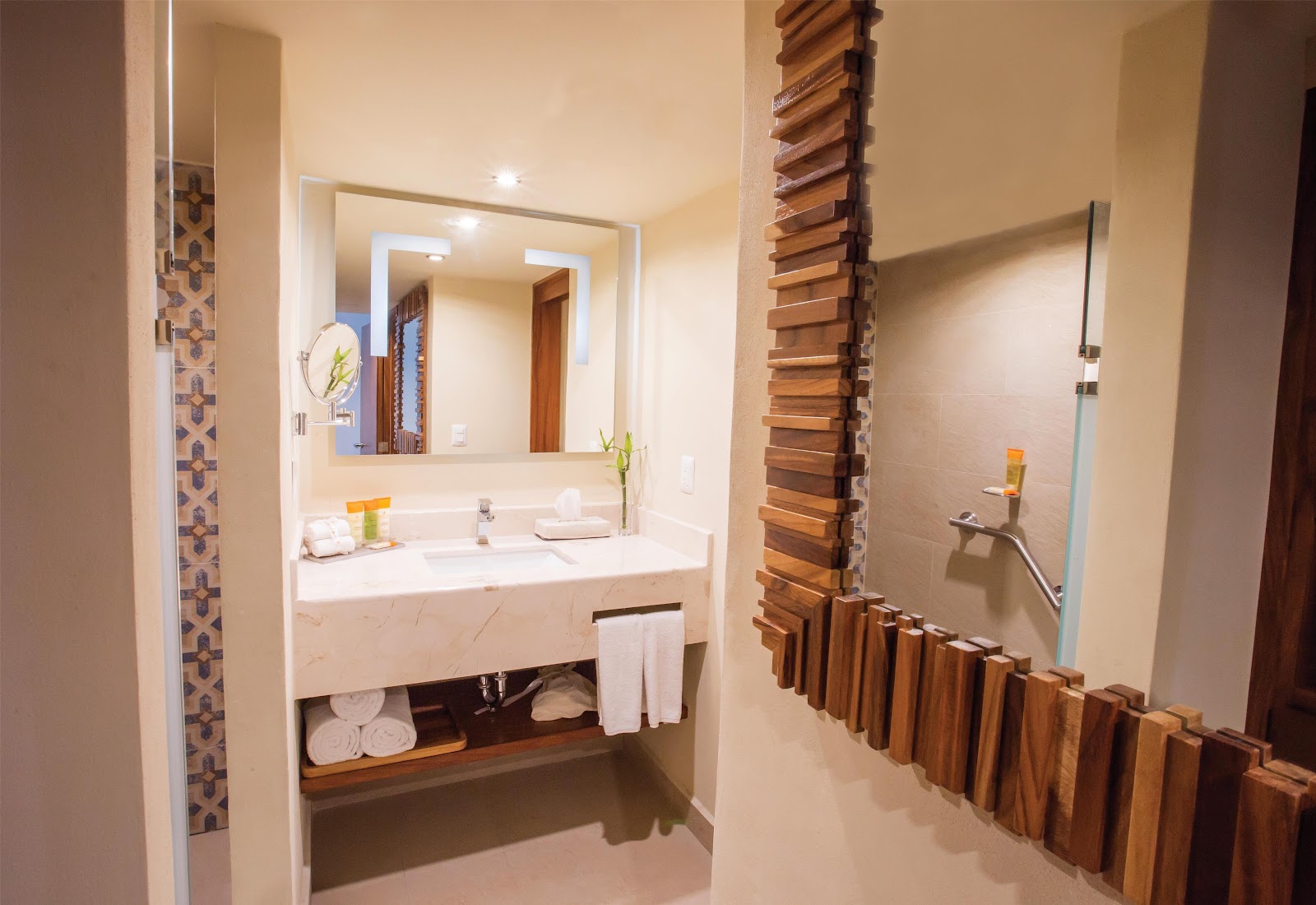 Modern bathroom with marble vanity, illuminated mirror, white towels, and wooden wall accents at Sunscape Puerto Vallarta Resort & Spa.