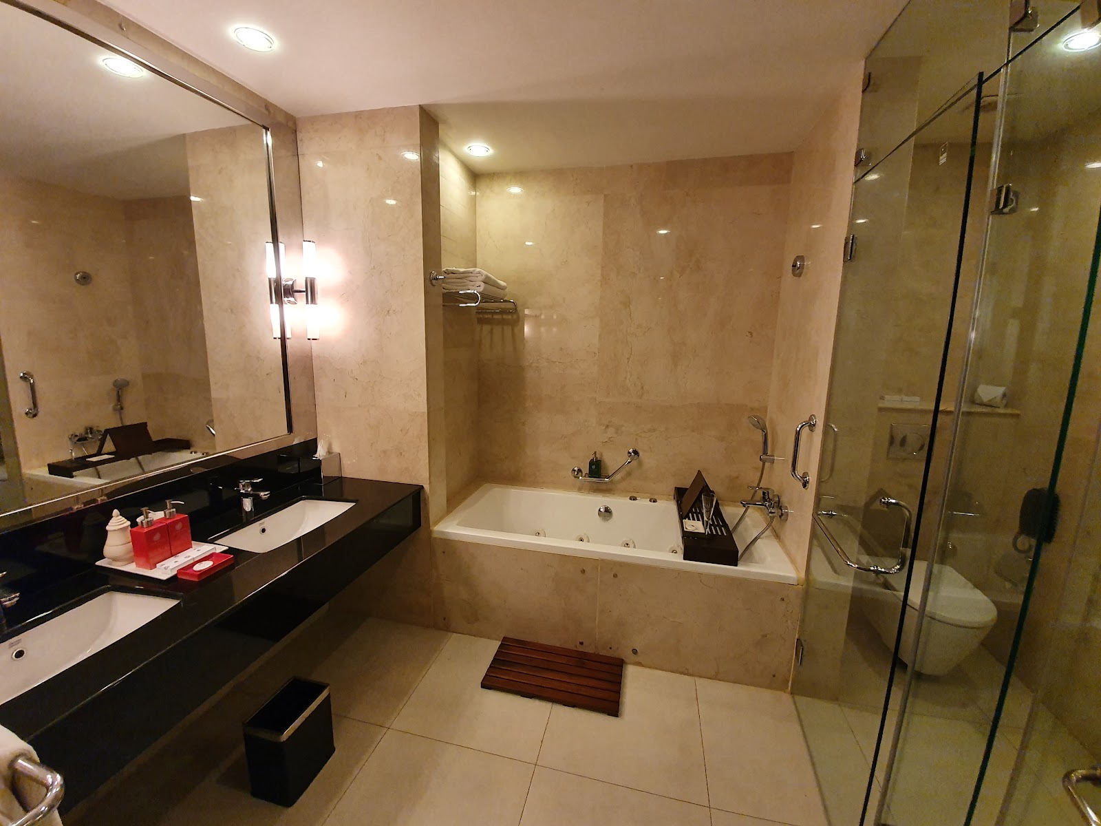 Marble bathroom with black vanity, soaking tub, and glass-enclosed shower stall with amenities and towels.