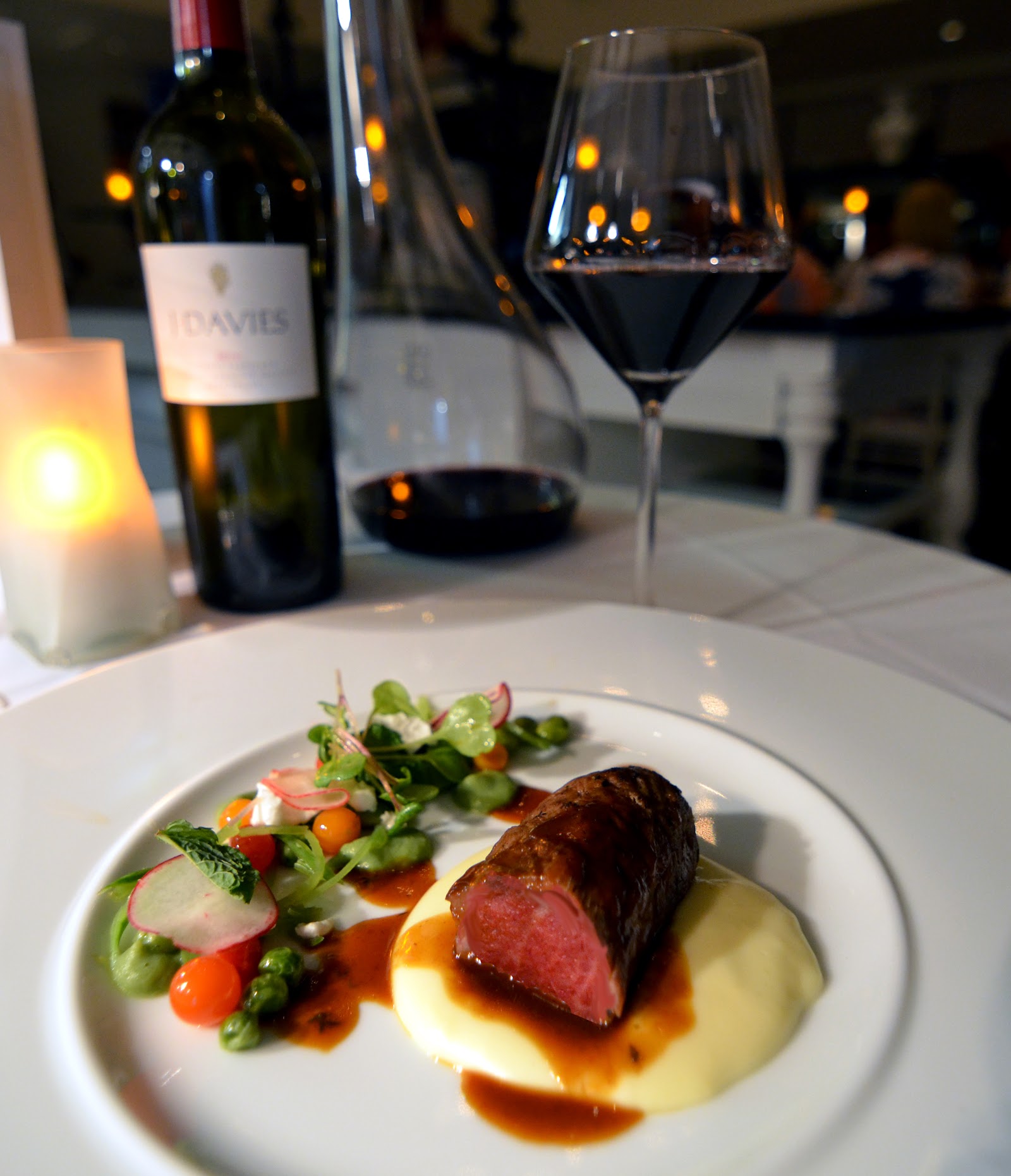 Plated beef and vegetables with red wine and candles at The BodyHoliday's fine dining restaurant.