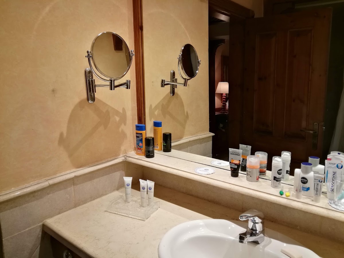 Bathroom vanity with two round mirrors, white sink, and toiletries lined along the counter at The Grand Resort Hurghada.