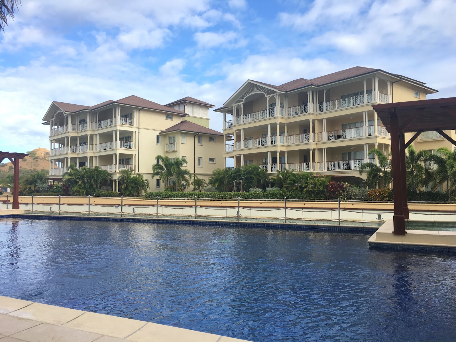 Waterfront view of multi-story resort buildings with boats docked at wooden piers in turquoise lagoon water under blue sky.