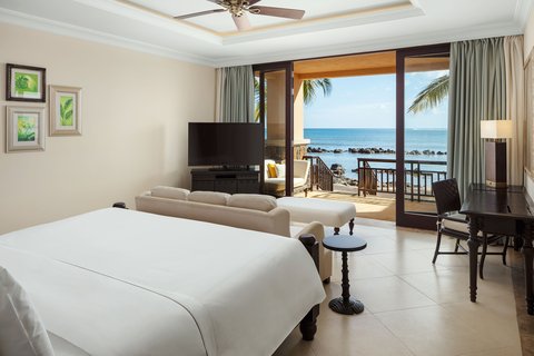 Spacious resort room with two queen beds, wooden furniture, and a balcony overlooking palm trees and ocean at The Westin Turtle Bay.