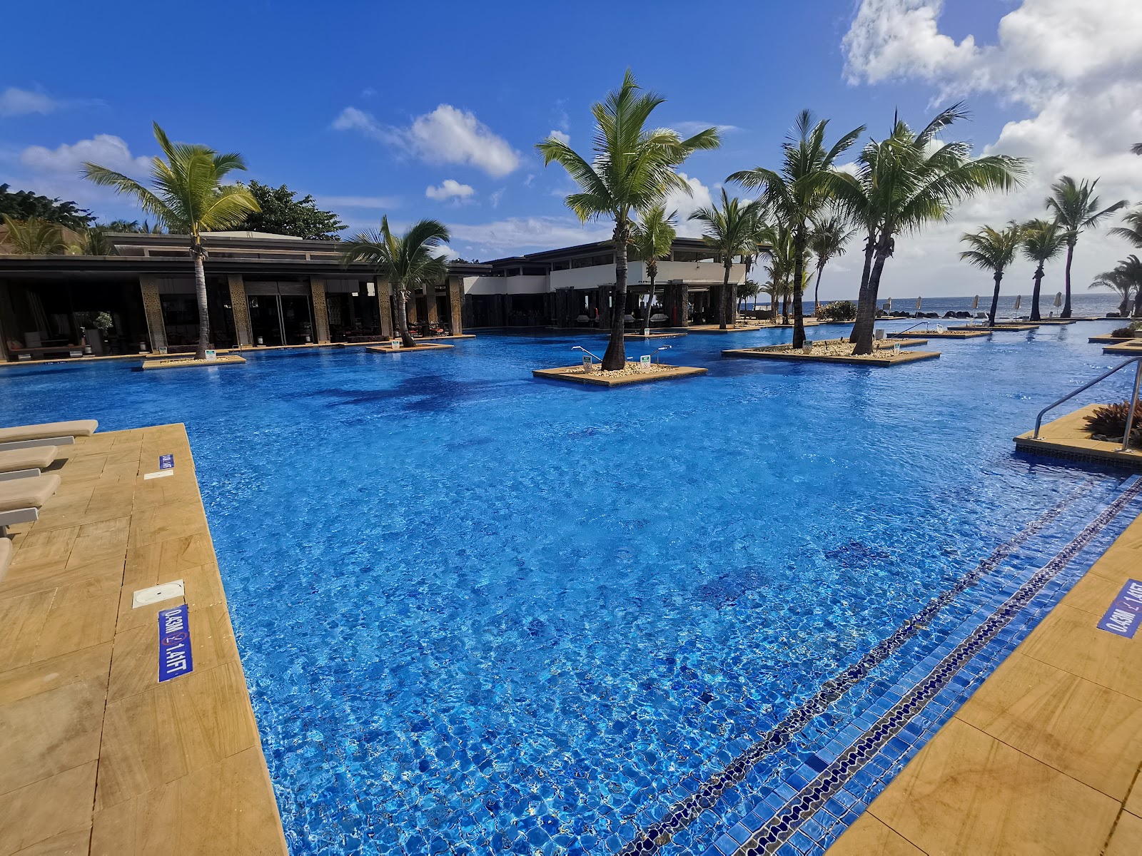 Large lagoon-style pool with depth marker, palm trees, and tropical landscaping overlooking the Indian Ocean at The Westin Turtle Bay Resort & Spa.