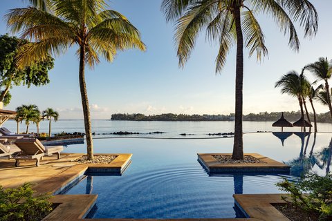 Infinity pool with glass railing overlooking the ocean, palm trees, and blue sky at The Westin Turtle Bay Resort & Spa.