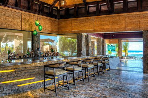 Thatched-roof dining pavilion at The Westin Turtle Bay overlooks a lagoon with white umbrellas, palm trees, and the ocean beyond.