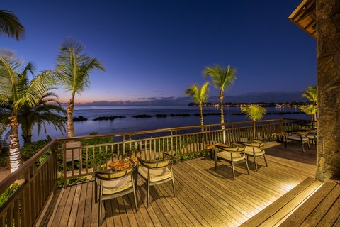 Paved pathway lined with tropical plants leading through palm trees to turquoise ocean waters under clear blue sky at The Westin Turtle Bay Resort & Spa.