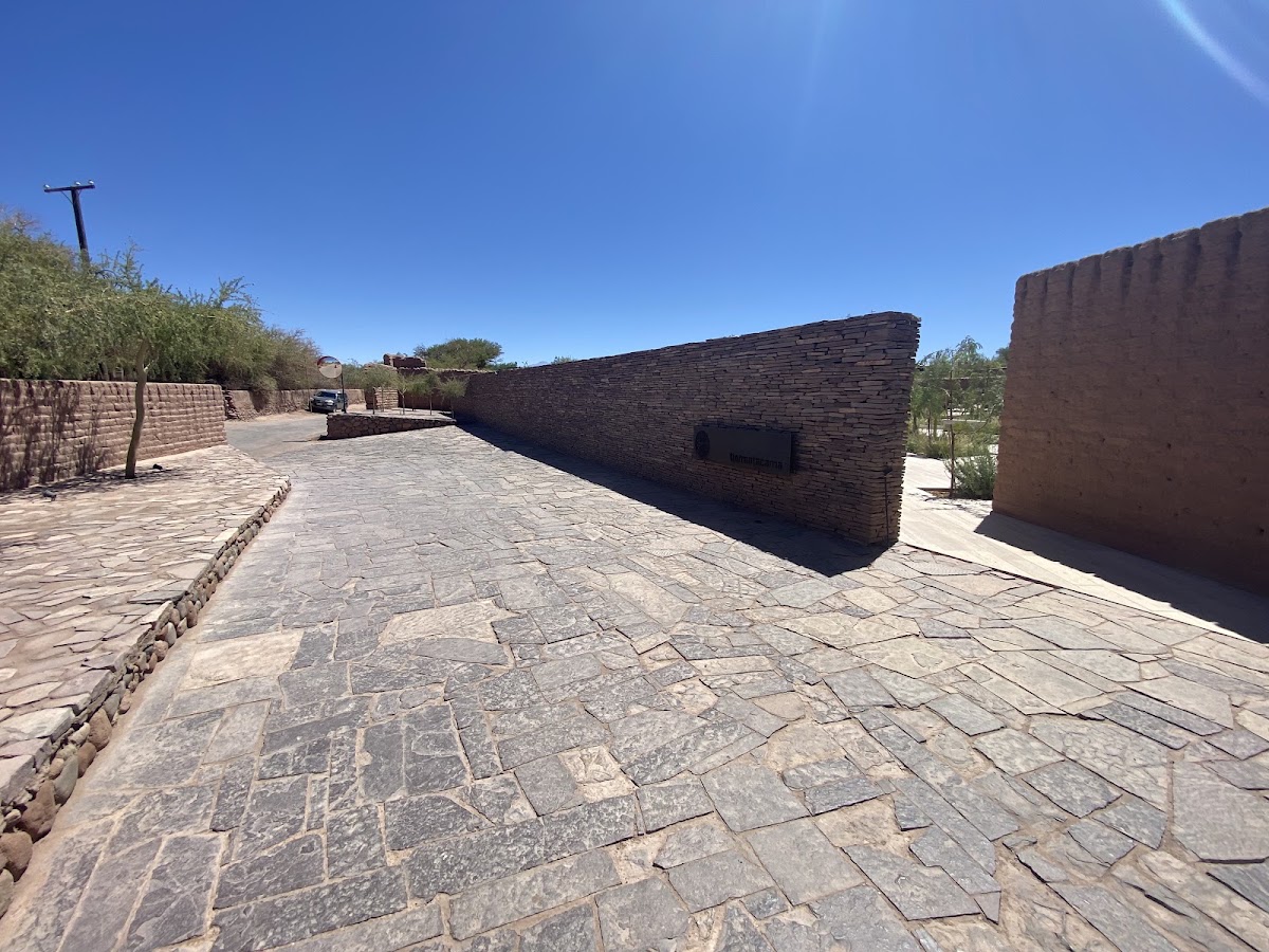 Stone courtyard at Tierra Atacama framed by rustic brick walls under clear blue sky.