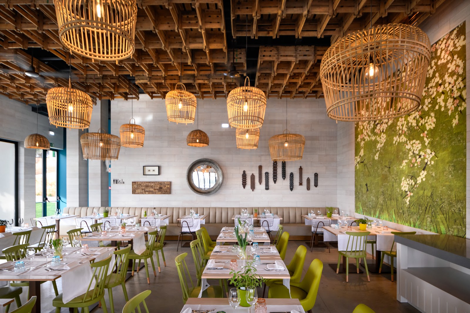 Modern dining room with woven pendant lights, green chairs, set tables, and botanical wall art at Tivoli Alvor Algarve.