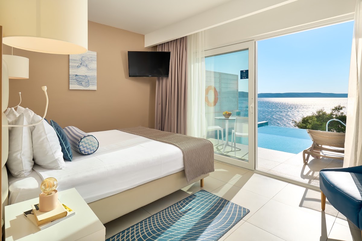 Beachfront suite at TUI BLUE Adriatic Beach with king bed, terrace access to infinity pool and Adriatic Sea beyond.