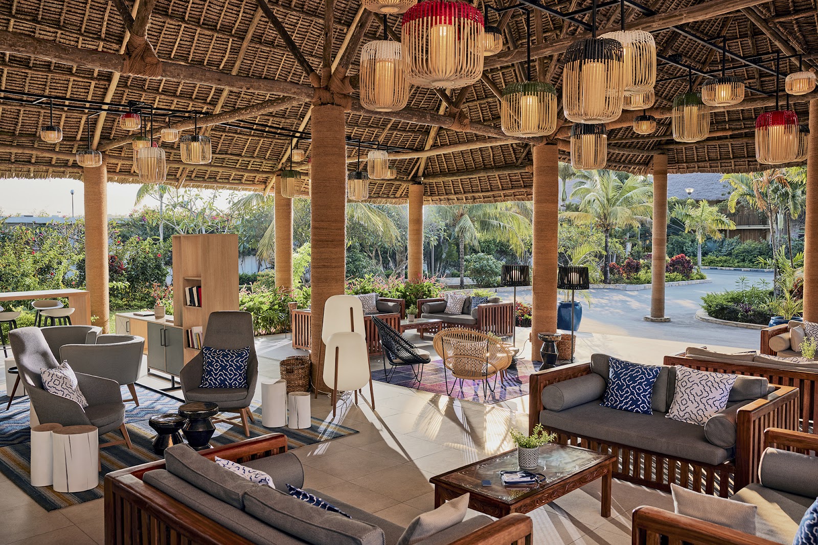 Large covered lounge area with woven pendant lights, wooden columns, and casual seating overlooking tropical gardens and water features at TUI BLUE Bahari Zanzibar.