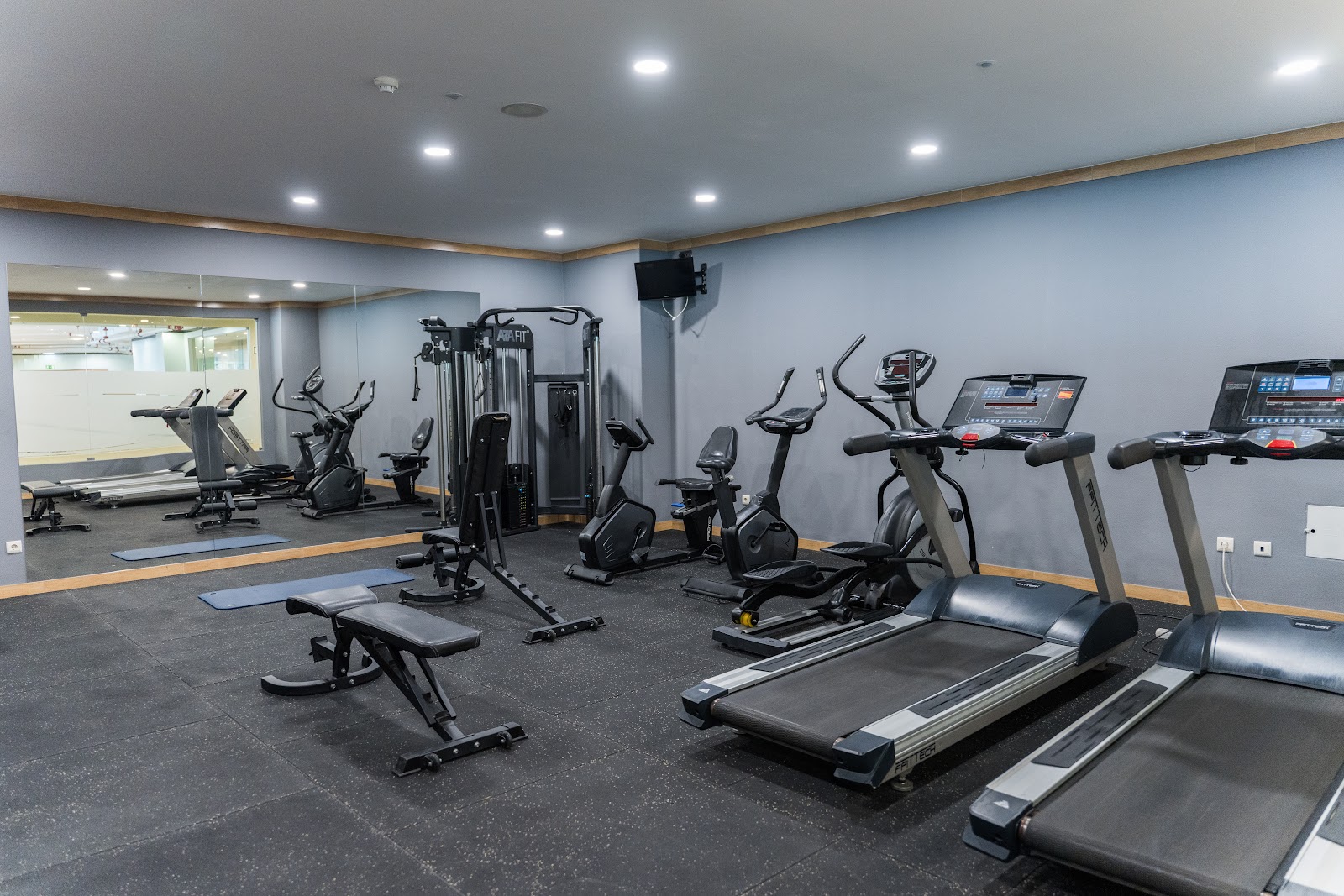 Modern fitness center with treadmills, stationary bikes, weight machines, and a mirrored wall at Ukino Palmeiras Village.