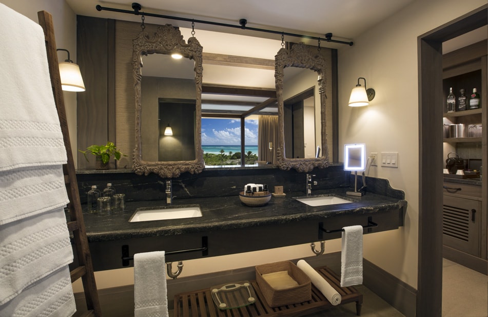 Bathroom with dual vanities, ornate mirrors, black countertop, and ocean view through window at UNICO 20°87° Hotel Riviera Maya.