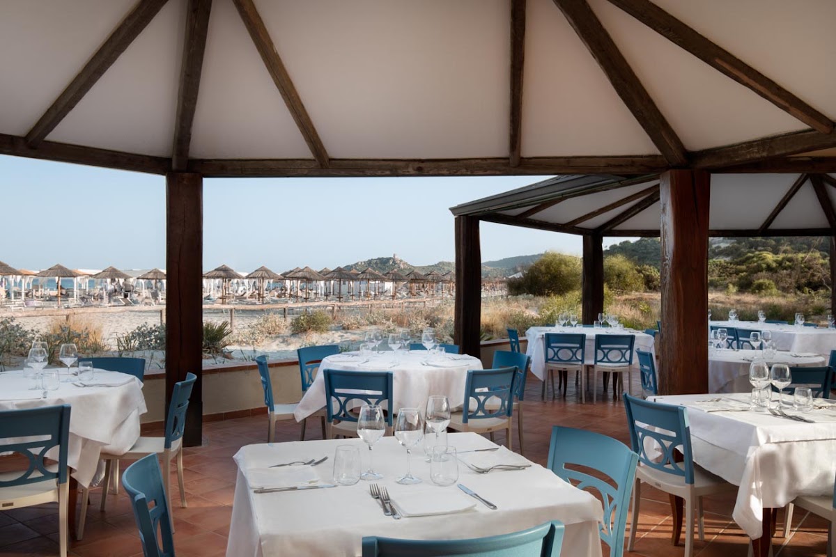 Dining pavilion with white tablecloths and blue chairs overlooking beach umbrellas and Mediterranean coastline at VOI Tanka Resort.