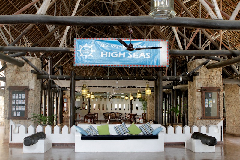 High Seas bar entrance at Voyager Beach Resort with white seating, blue signage, and nautical-themed wooden beam ceiling.