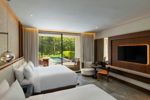 Modern resort bedroom with two beds, wall-mounted TV, and sliding glass doors opening to manicured grounds at W Punta Cana.