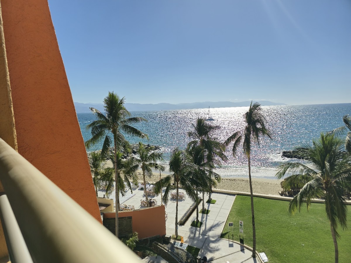 Palm trees line a manicured lawn beside a sandy beach and sparkling ocean at The Westin Playa Vallarta.