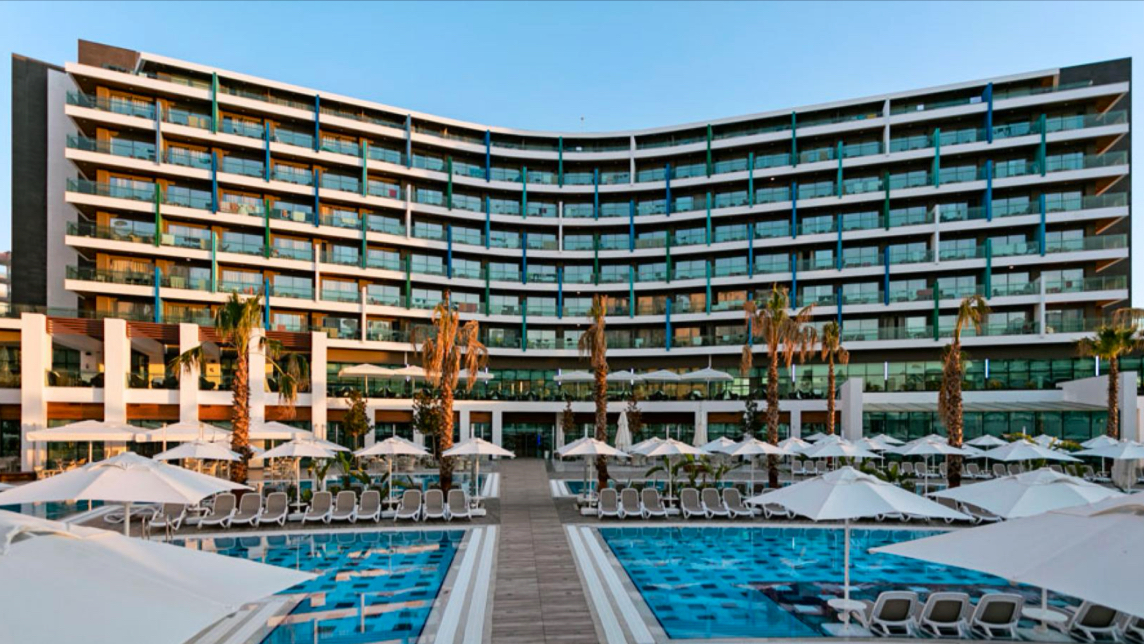 Wind of Lara Hotel & Spa's multi-story atrium features a spiraling crystal chandelier hanging beneath skylights, with guest room balconies lining the walls.