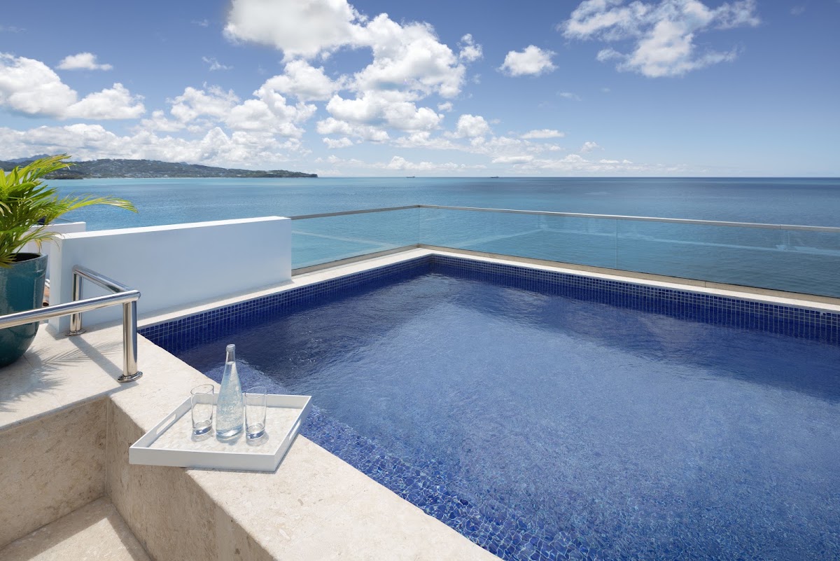 Private infinity pool on an oceanfront terrace overlooking blue waters and forested coastline at Windjammer Landing Resort & Residences.