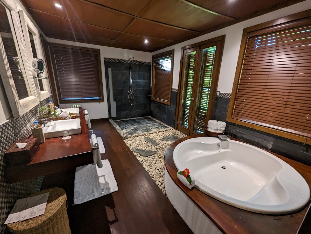 Spacious bathroom at Zoëtry Agua Punta Cana with soaking tub, dual vanity, walk-in shower, and wooden louvered windows.
